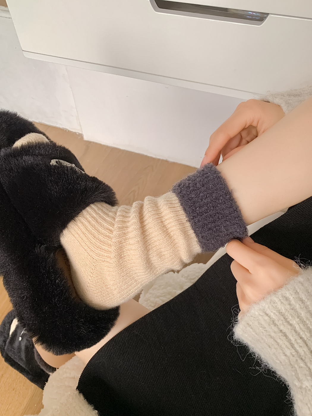 Close-up of the cream sock's ribbed texture and dark gray fuzzy fold-over cuff