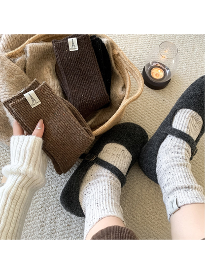Ivory speckled crew socks worn with charcoal clogs beside folded brown socks