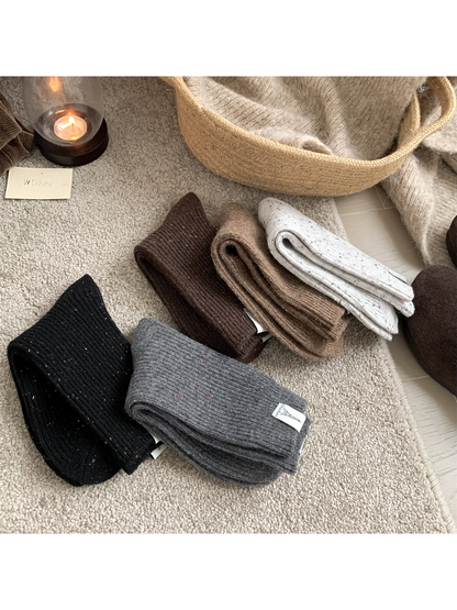 Folded ribbed crew socks showing speckled knit texture in five neutral colors