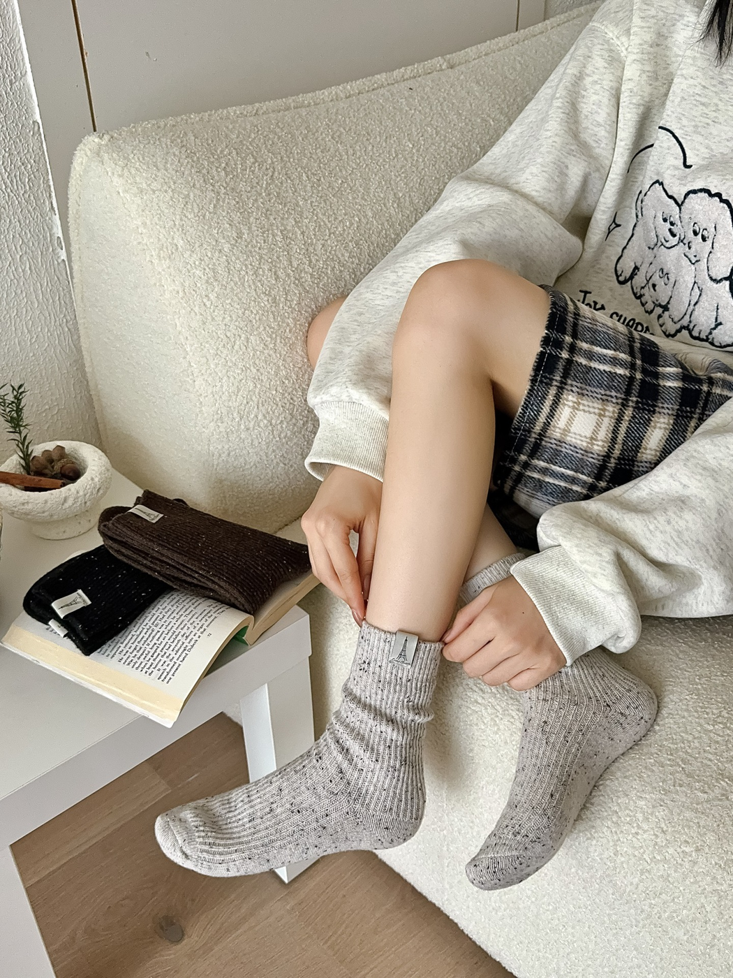 Ivory speckled crew socks worn with a plaid skirt in an indoor seating area