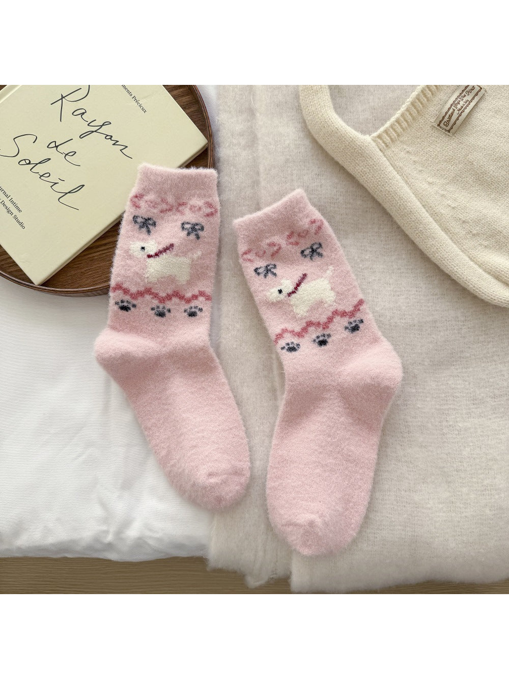 Light pink fuzzy crew socks with a white dog motif and bow accents