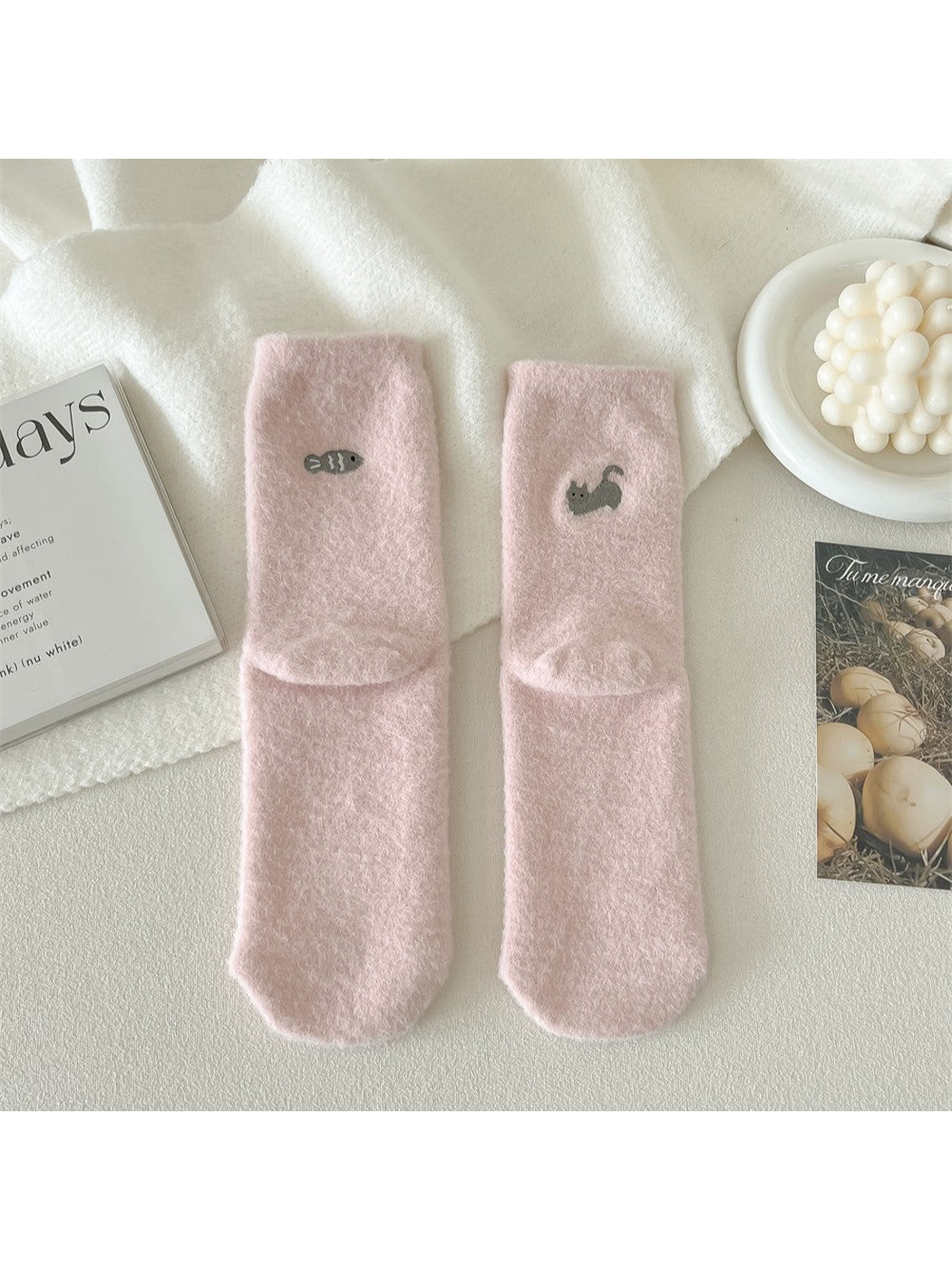 Light pink fuzzy socks with small cat and fish motifs on the backs