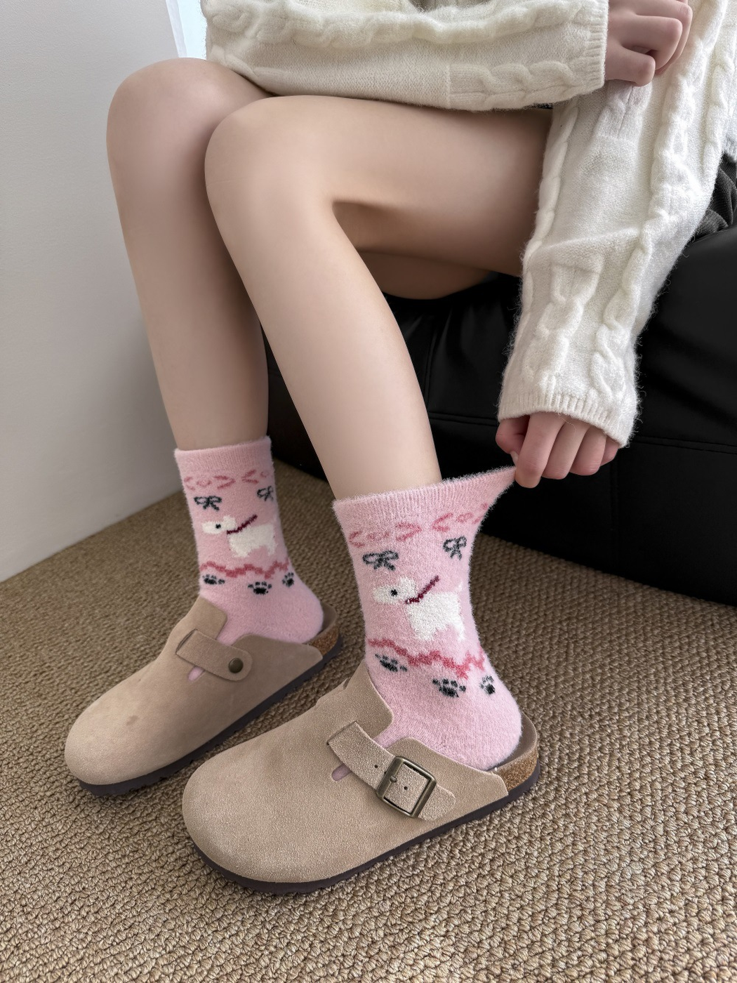 Light pink dog-motif fuzzy socks worn as a pair with beige clogs