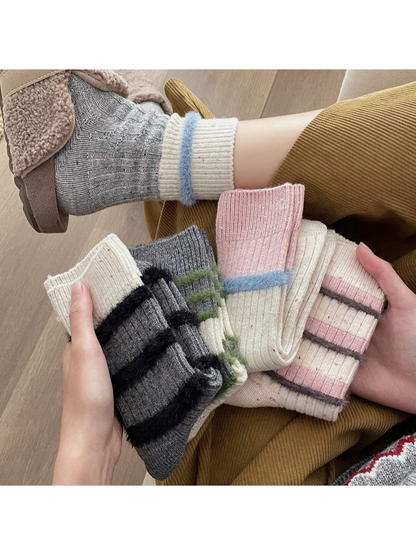 Five fuzzy-trim crew sock designs held beside a worn gray pair