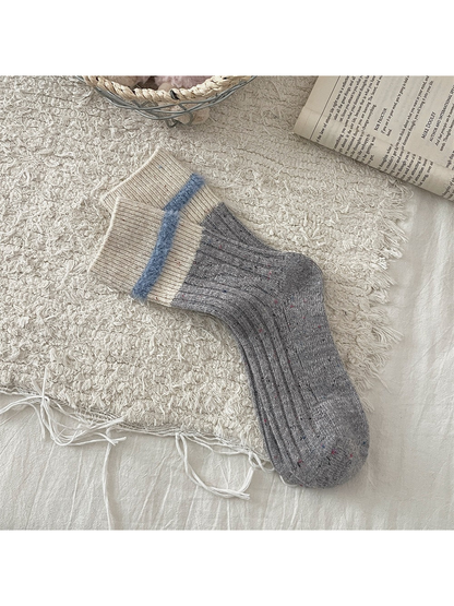 Gray speckled crew socks with cream cuffs and blue fuzzy trim