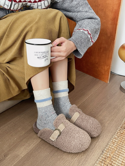 Gray speckled crew socks with cream cuffs worn with fuzzy clogs
