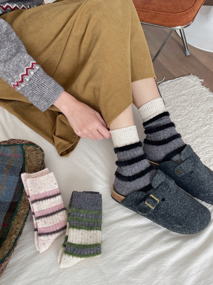 Dark gray crew socks with cream cuffs and black fuzzy stripes worn with clogs