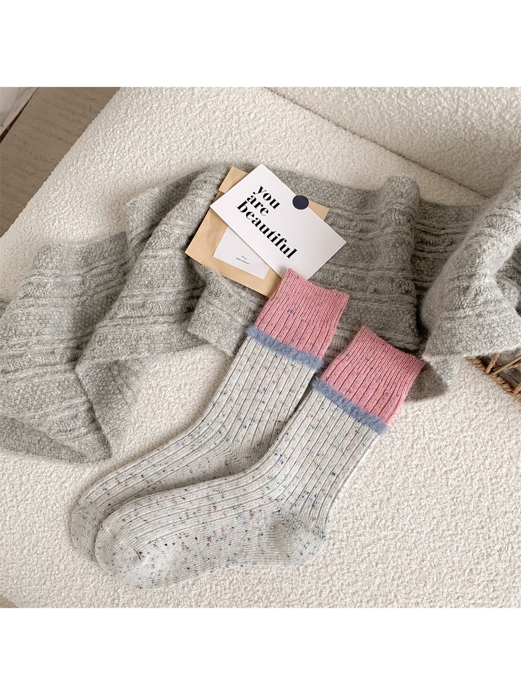 Light gray speckled crew socks with pink cuffs and pale blue fuzzy trim