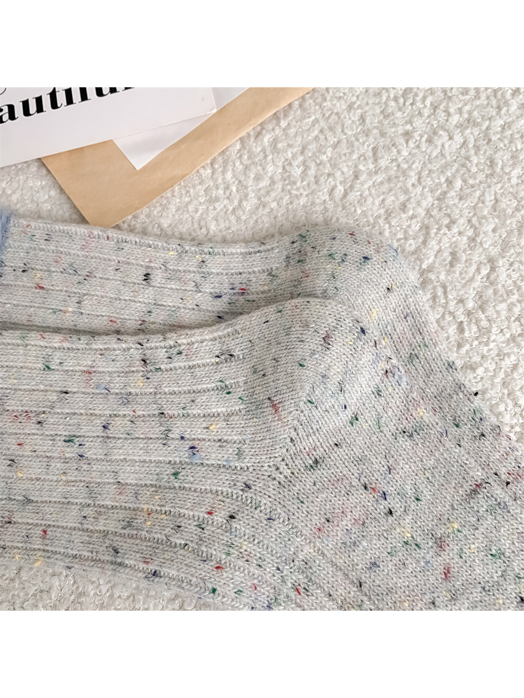 Close-up of multicolor flecks across the gray ribbed knit
