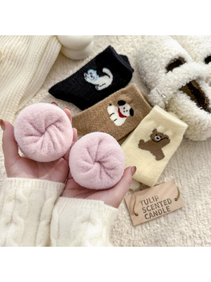 Close-up of rolled pink fuzzy socks with animal-motif styles in the background