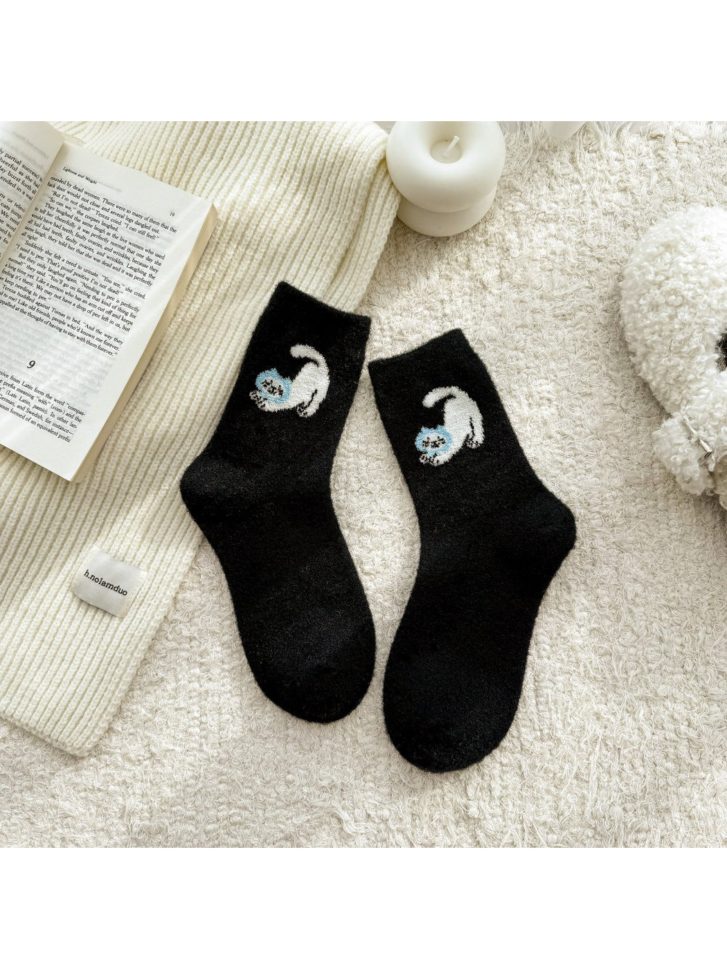 Black fuzzy socks with white cat motifs and blue accents