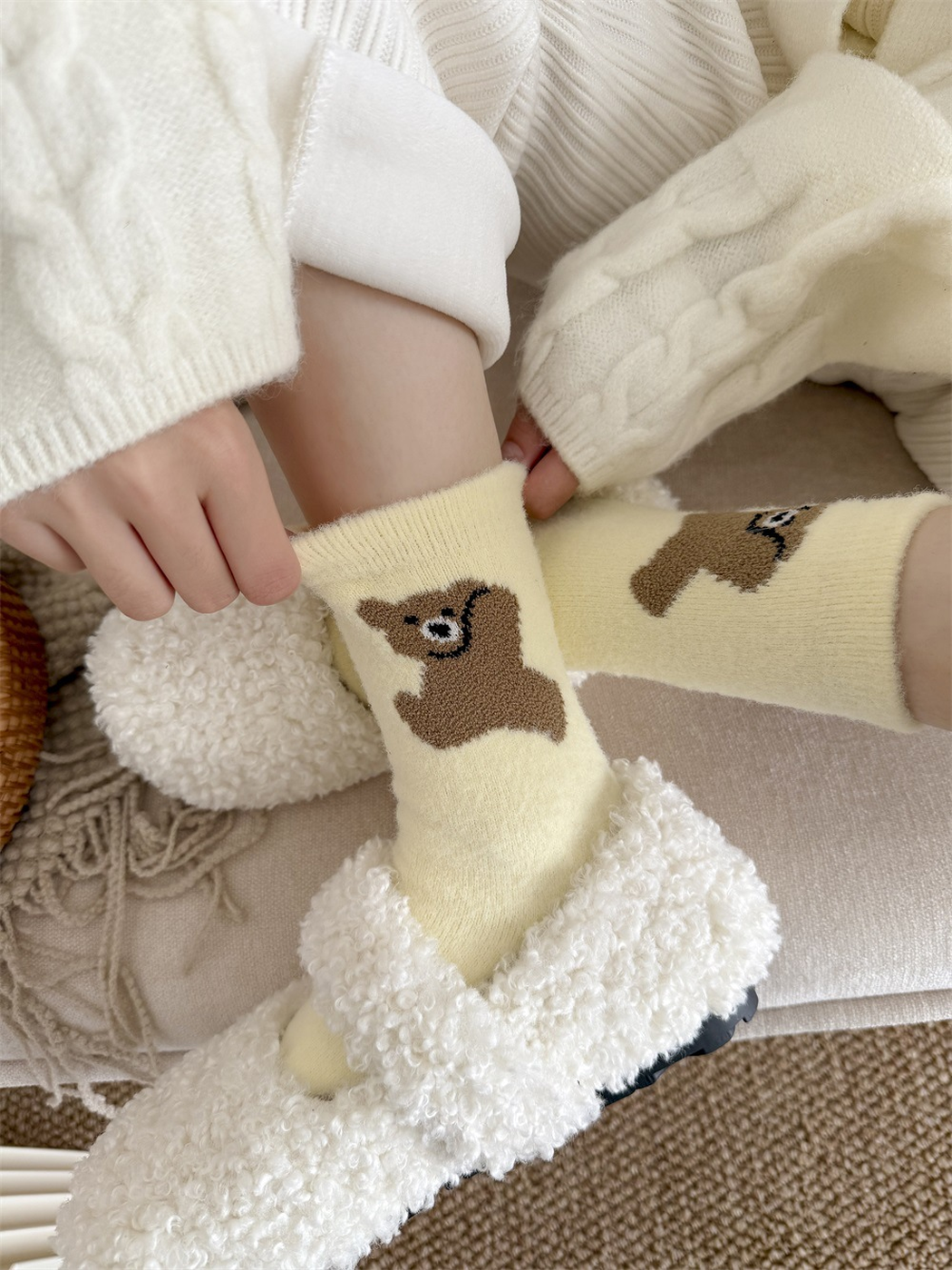 Close-up of pale yellow bear-motif socks showing the ribbed top opening