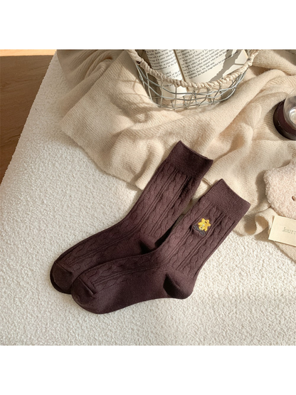 Dark brown cable-knit crew socks with embroidered yellow flower