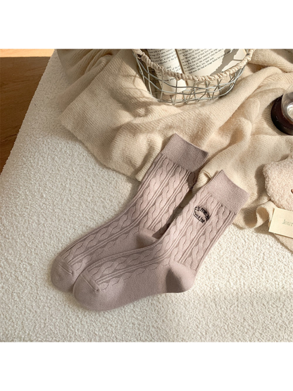 Light taupe cable-knit crew socks with embroidered text motif
