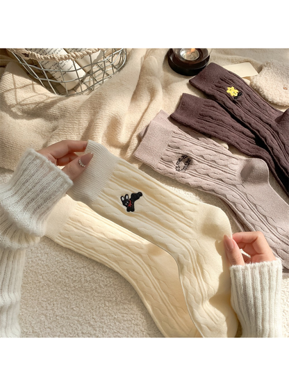 Close-up of ivory cable-knit socks and embroidered rabbit motif