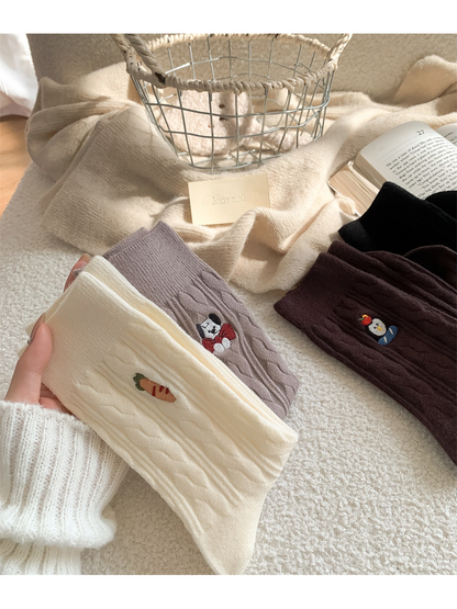 Ivory, light taupe and dark brown cable-knit socks held beside folded pairs