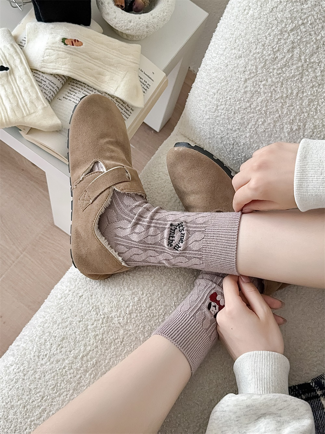 Light taupe cable-knit crew socks worn with tan clogs in a seated view