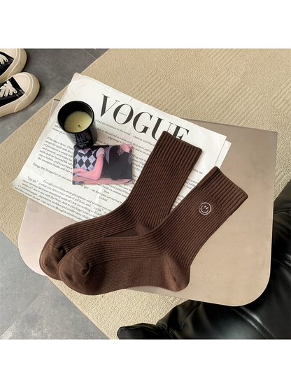 Brown ribbed crew socks with embroidered smiley motif, pair laid flat