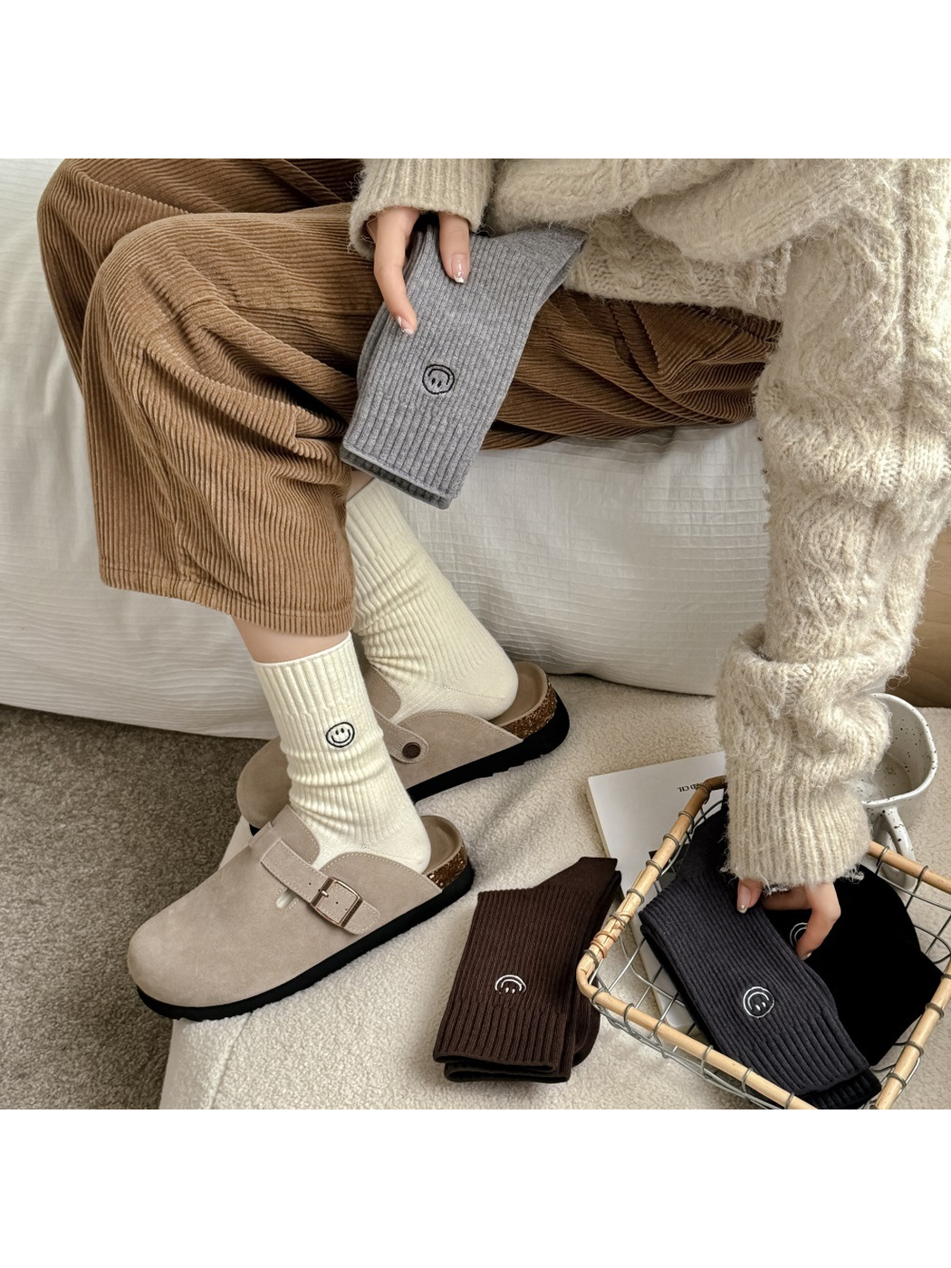 Cream smiley crew socks worn with clogs beside folded color variants