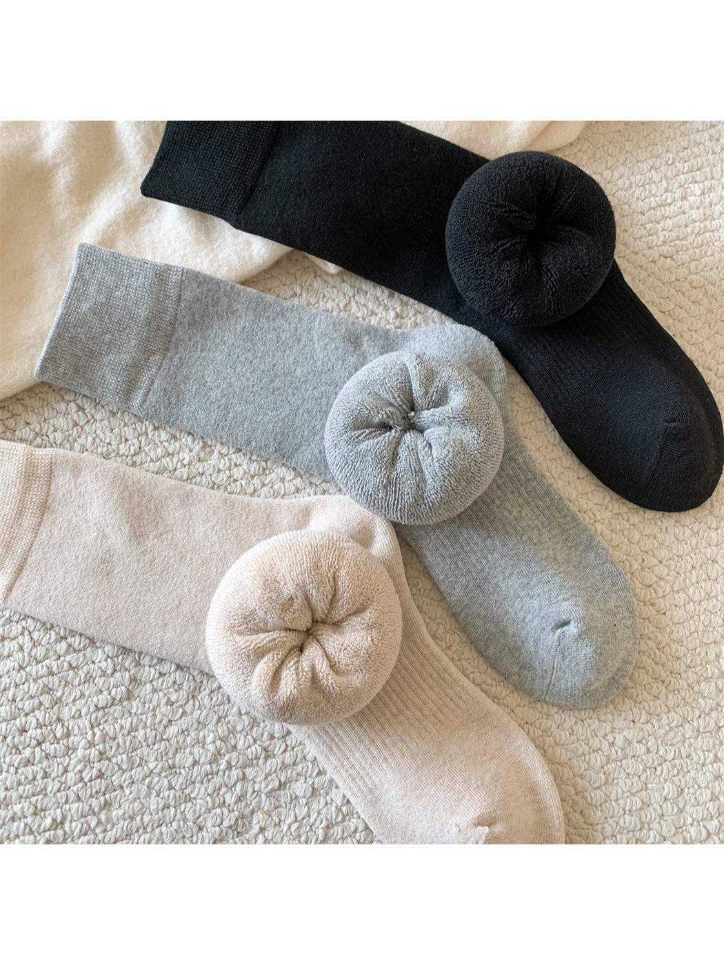 Close-up of black, light gray and khaki socks with rolled interiors