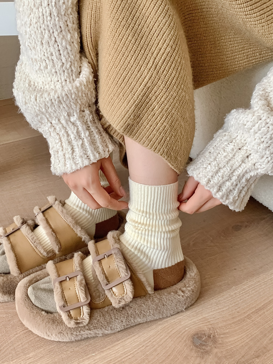 Cream ribbed crew socks worn gathered above plush sandals
