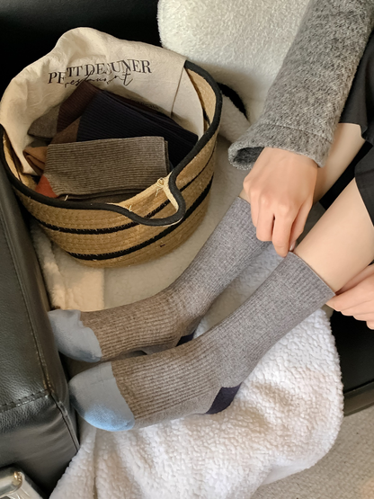 Gray color-blocked ribbed crew socks worn in a seated indoor setting