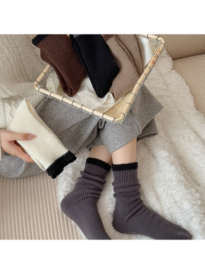 Dark gray crew socks worn beside folded ivory, black, camel and brown pairs