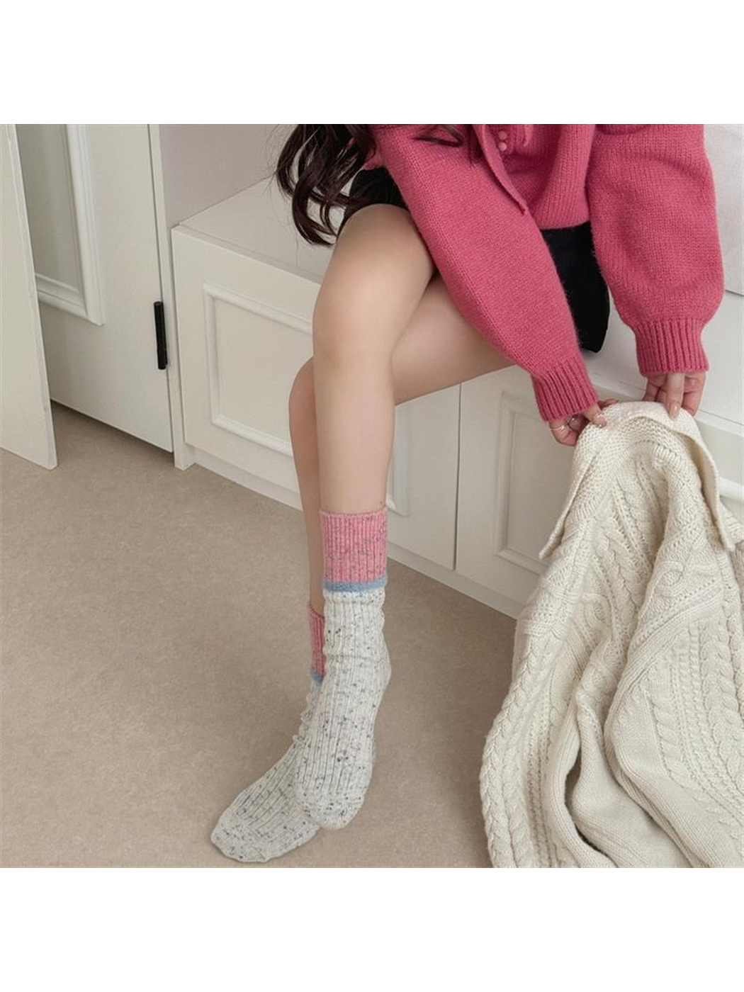 Ivory speckled crew socks with pink cuffs worn in a seated setting