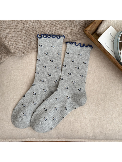 Gray crew socks with tiny floral motifs and navy wavy cuffs