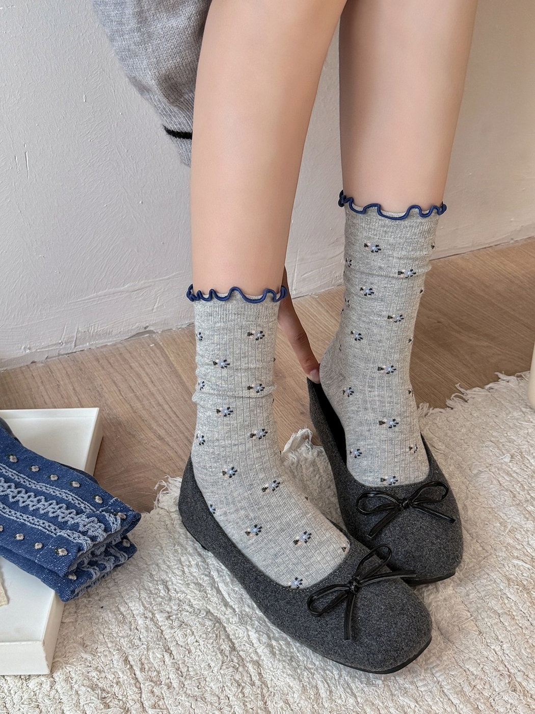 Gray floral crew socks worn with charcoal bow flats