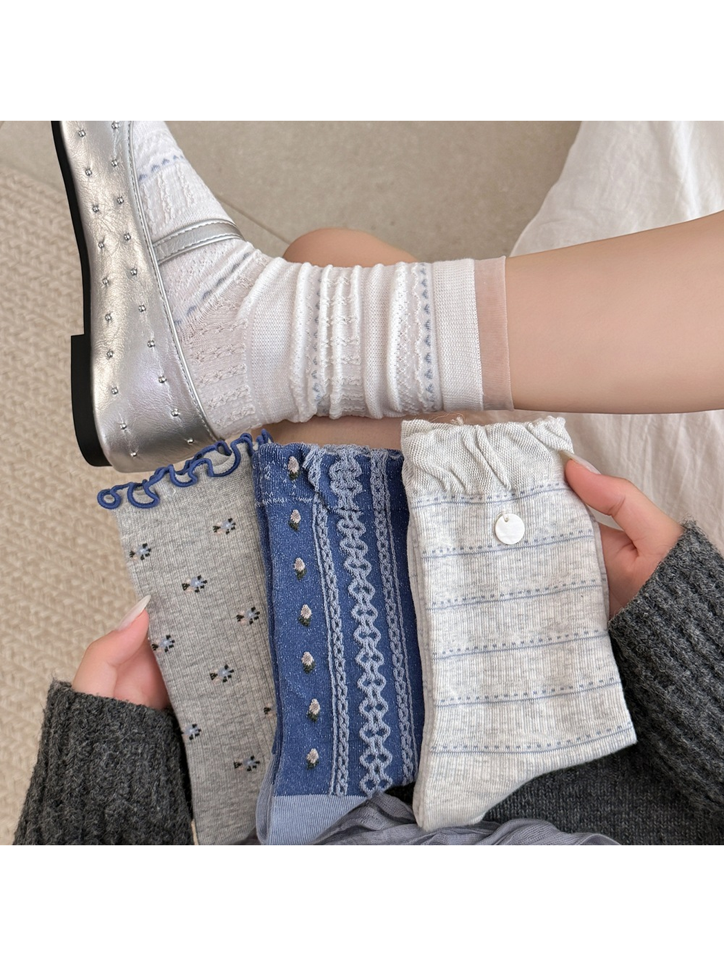 Gray floral, blue patterned and light gray striped socks held beside a worn white sock