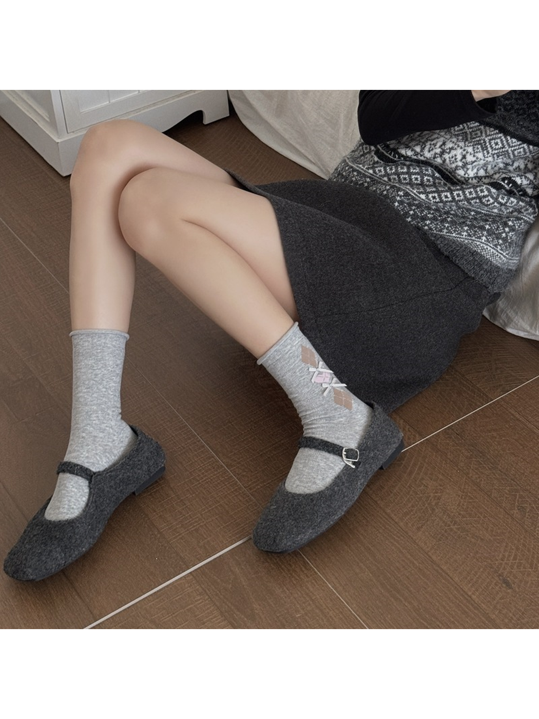 Light gray argyle bow crew socks styled with charcoal Mary Jane shoes