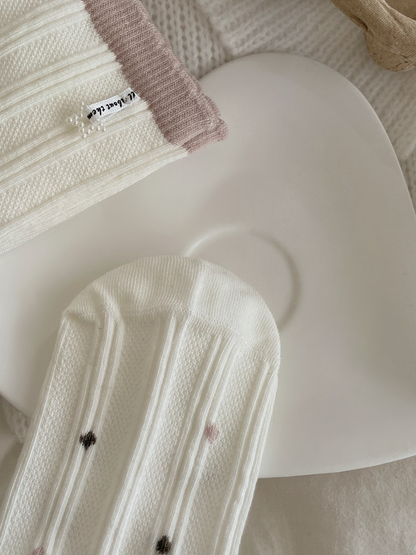Close-up of ivory ribbed socks with brown and pink dot motifs