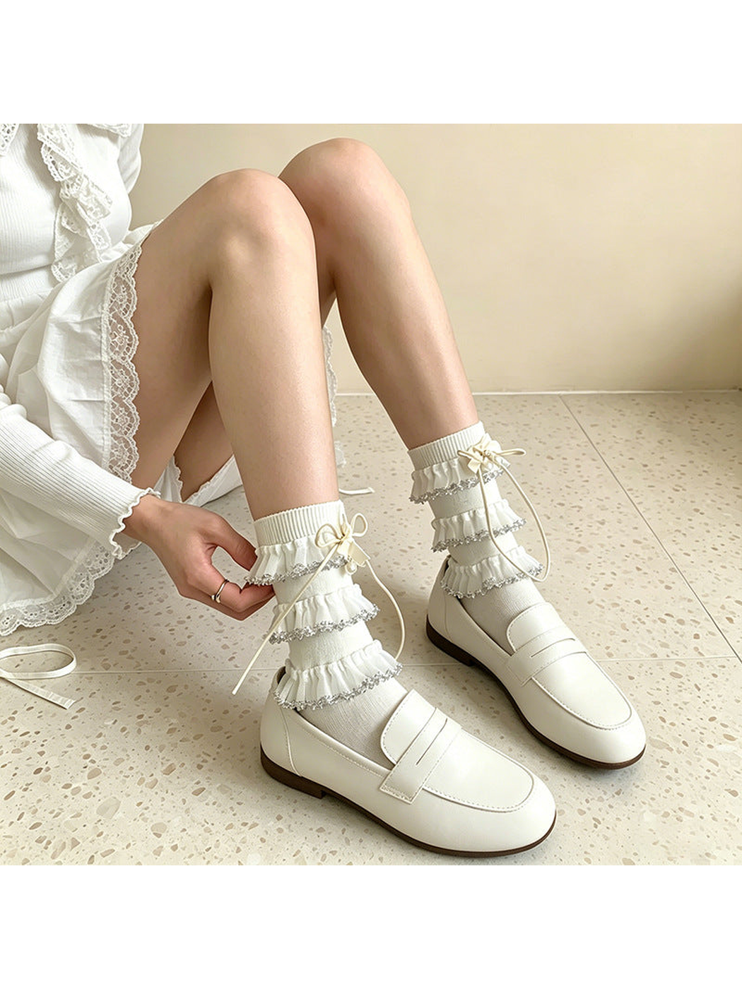 White ruffle socks styled with loafers in a seated view