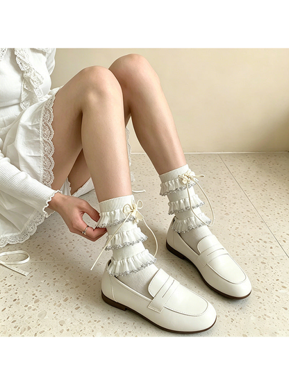 White ruffle socks styled with loafers in a seated view