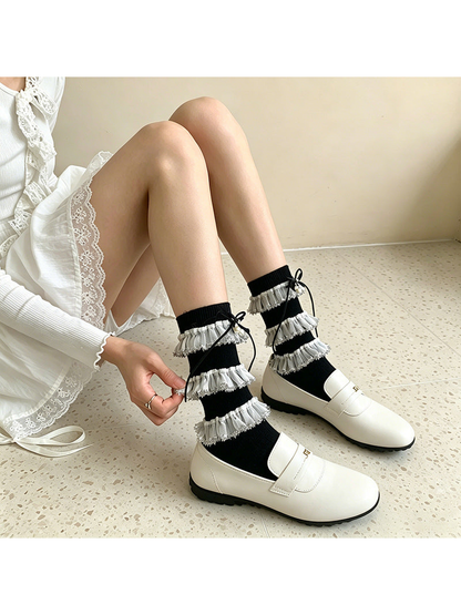 Black tiered-ruffle socks styled with white loafers in a seated view