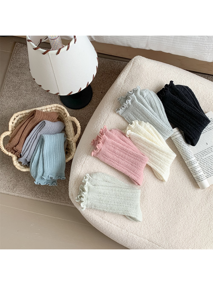 Assorted ribbed ruffle-cuff socks arranged in a home setting