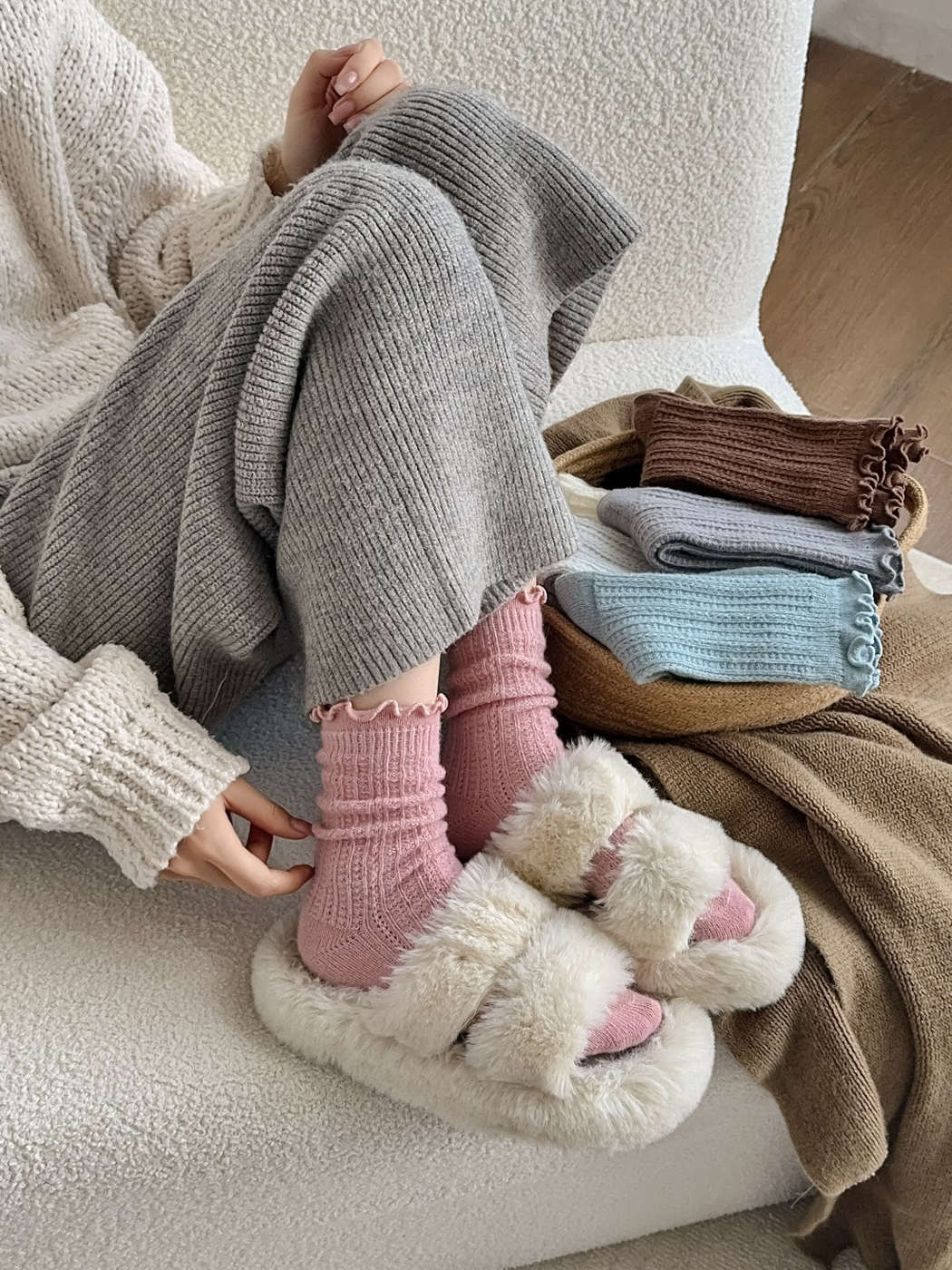 Pink ruffle-cuff socks worn with plush slippers beside folded color options
