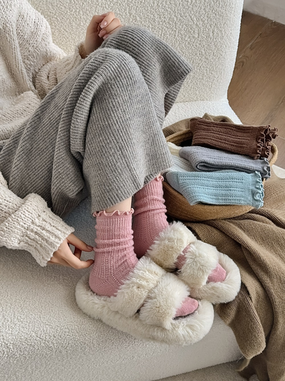 Pink ruffle-cuff socks worn with plush slippers beside folded color options
