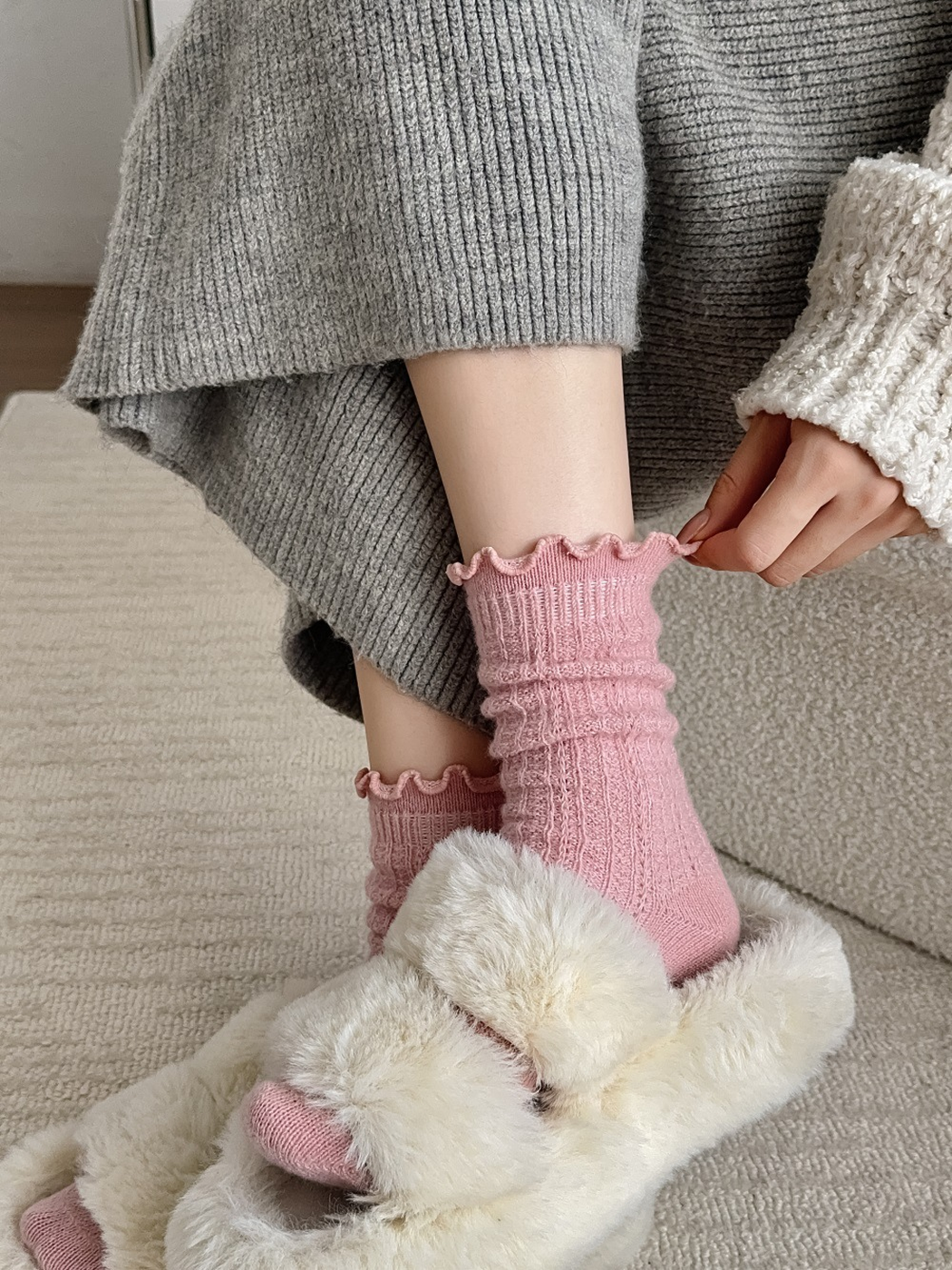 Pink ribbed socks worn scrunched above plush slippers