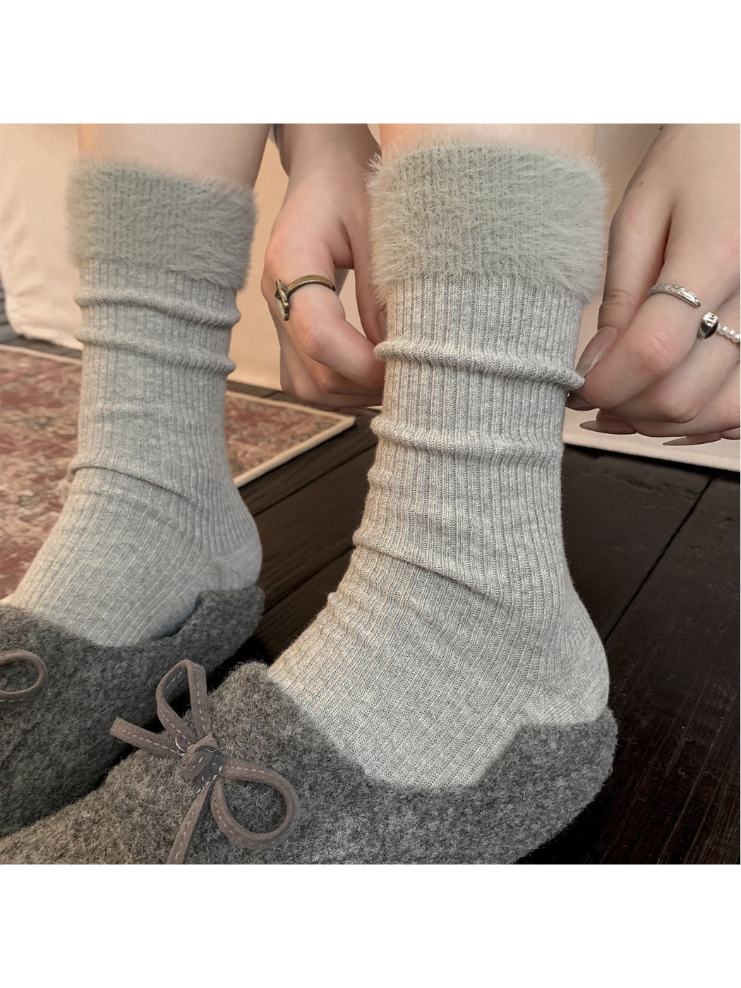 Light gray ribbed crew socks with fuzzy cuffs worn with gray slippers