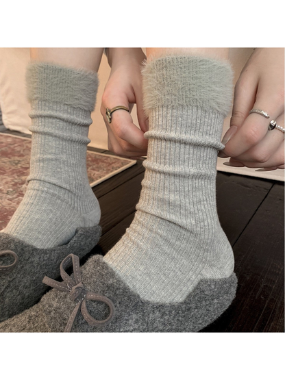 Light gray ribbed crew socks with fuzzy cuffs worn with gray slippers
