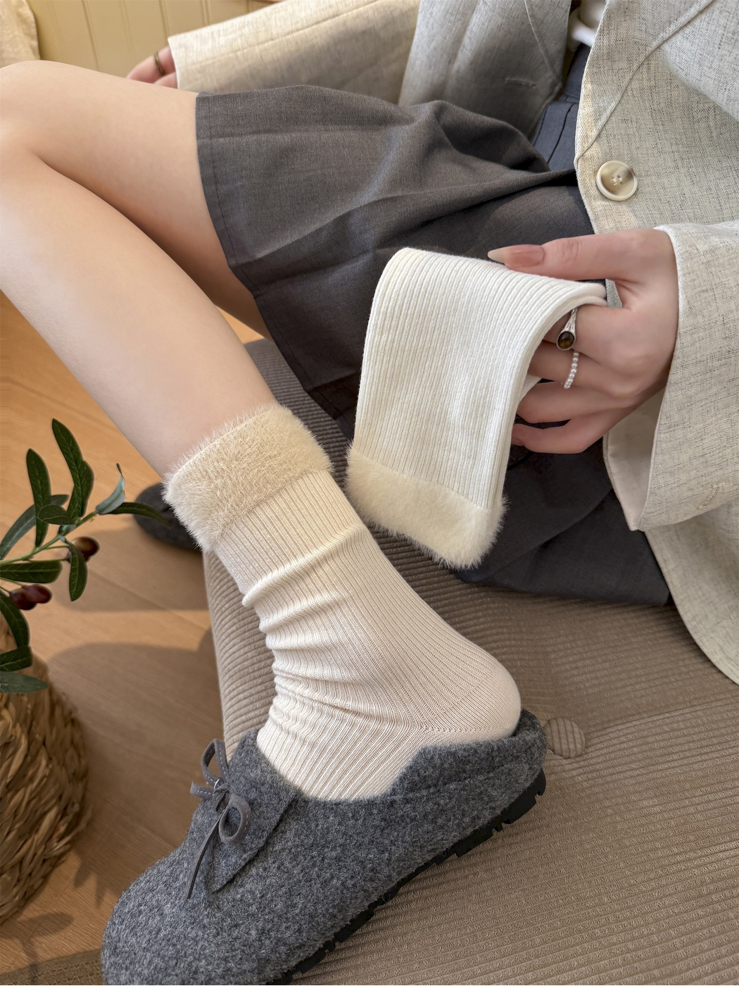 Cream ribbed crew sock with fuzzy cuff worn with a gray shoe beside a white sock