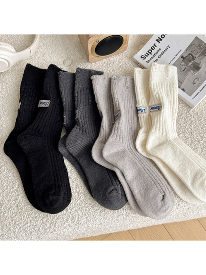 Black, dark gray, light gray and ivory ribbed crew socks displayed together