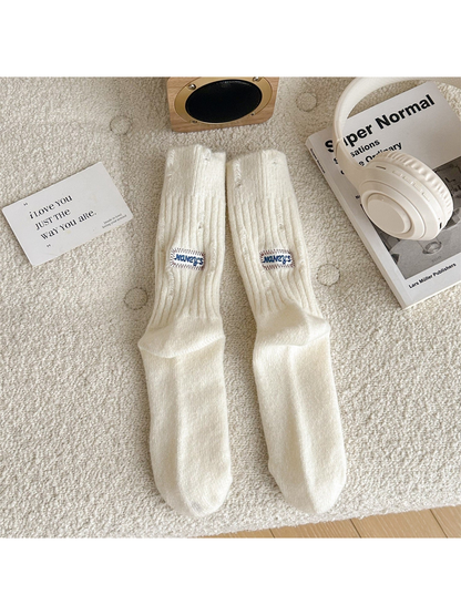 Ivory ribbed crew socks with distressed openings and sewn label patches