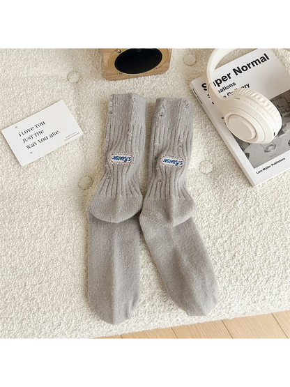 Light gray ribbed crew socks with distressed openings and sewn label patches