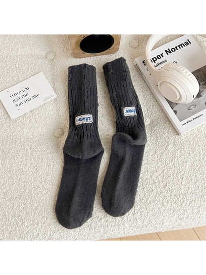 Dark gray ribbed crew socks with distressed openings and sewn label patches