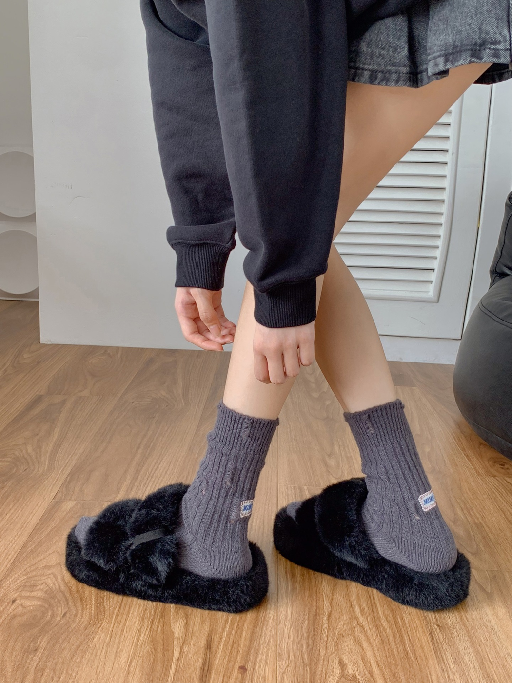 Dark gray ribbed crew socks styled with black fuzzy sandals