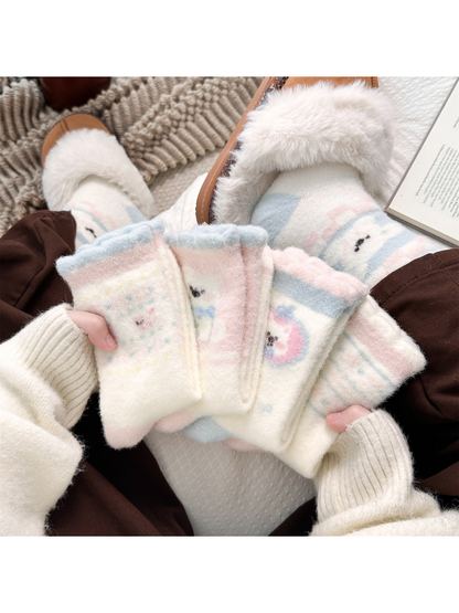 Pastel fuzzy crew socks displayed by hand beside matching slipper styling