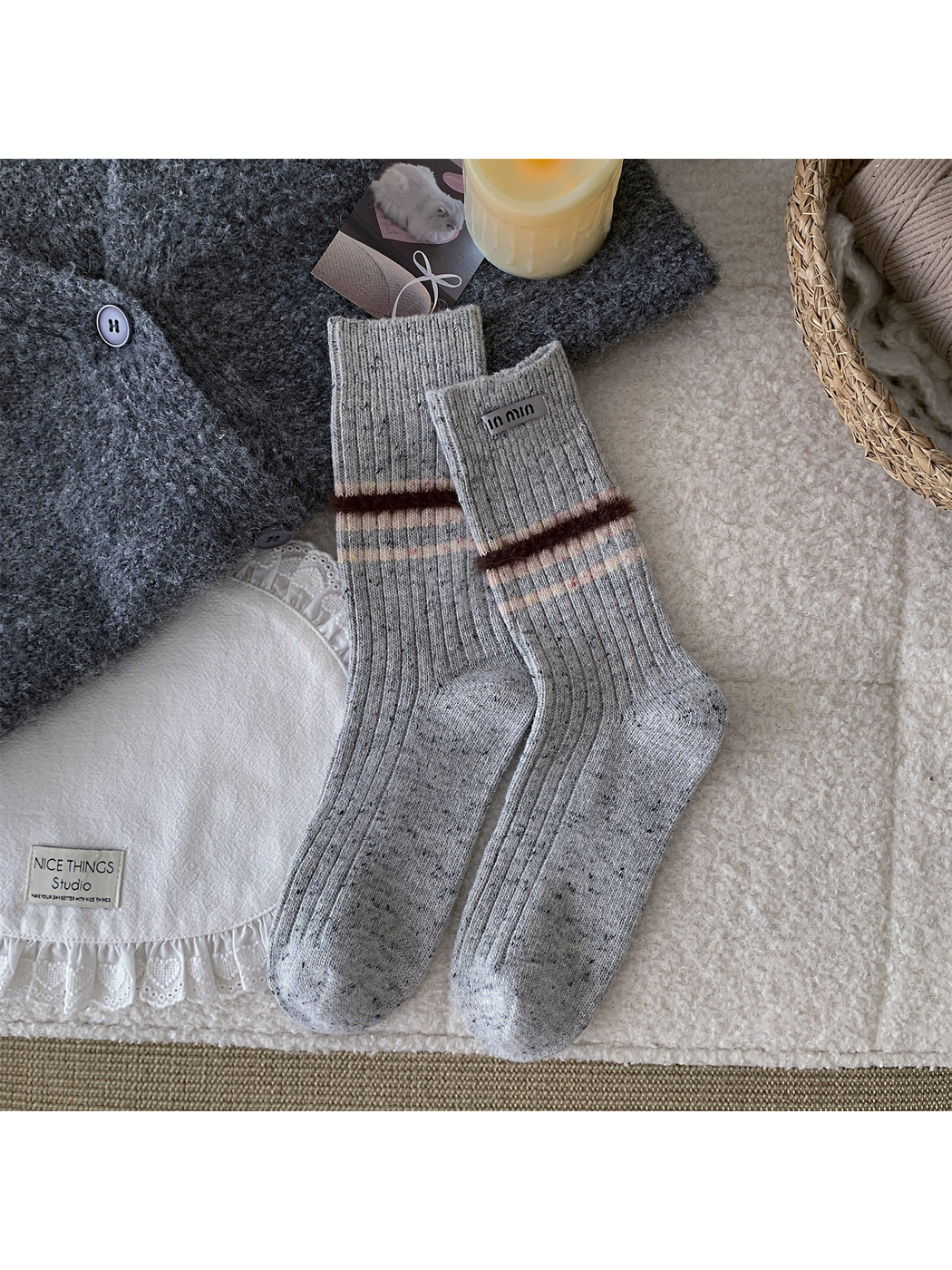 Light gray crew socks with a fuzzy brown band and narrow pastel stripes